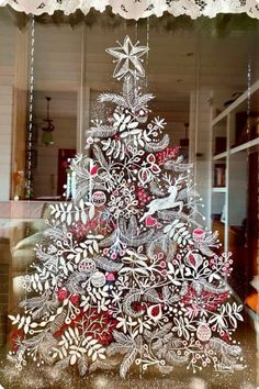 a christmas tree made out of cut outs on display in a glass case with lace trim