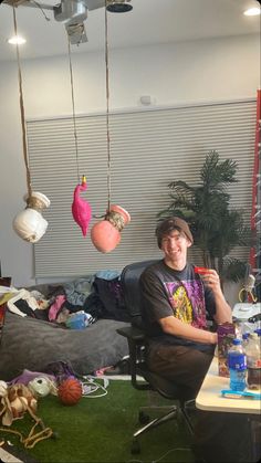 a man sitting on a chair in front of a pile of clutter and toys