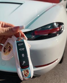 a hand holding a car key in front of a white sports car