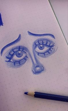 a drawing of a woman's face with blue eyes and eyebrows, on top of a notebook