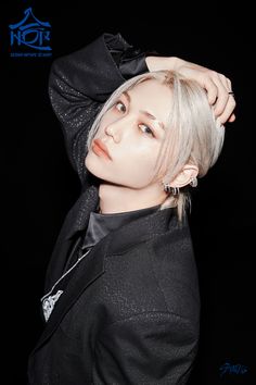 a woman with blonde hair wearing a black jacket and silver earrings is posing for the camera