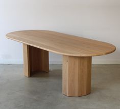 a large wooden table sitting on top of a cement floor next to a white wall