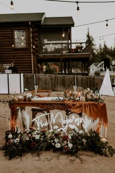 the table is set up with candles, flowers and greenery for an outdoor wedding