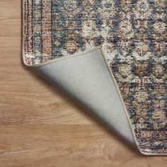 an area rug with a wooden floor and wood floors in the background, including a light colored area rug