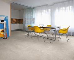 a dining room table with yellow chairs and a painting on the wall in the background