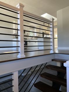 the stairs lead up to an open kitchen and dining area in a house with white walls