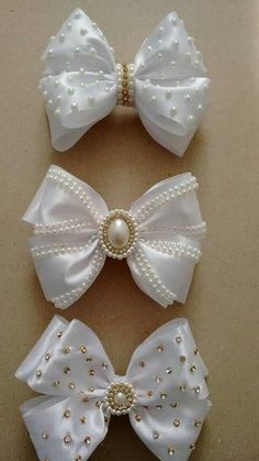 three white bows with pearls on them sitting next to each other in front of a wall