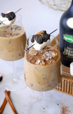 two glasses filled with ice cream and marshmallows on top of a table