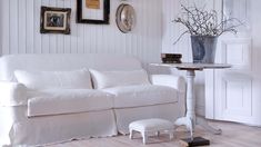 a living room with white furniture and pictures on the wall