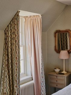 a bed sitting under a window next to a dresser with a mirror on top of it