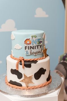 a birthday cake decorated with black and white cow print, gold stars and the words to one finty & beyond