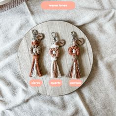 three keychains with different tassels on top of a white plate next to a bottle opener