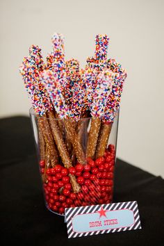 a glass filled with candy canes and sprinkles on top of a table