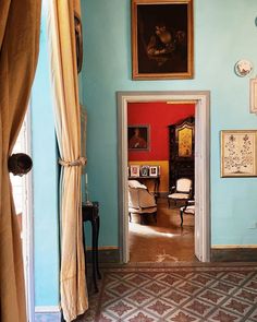 an open door leading to a living room with blue walls and paintings on the wall