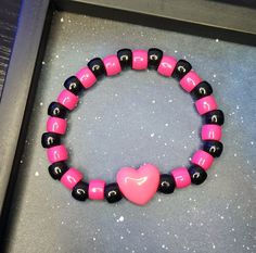 Edgy Adjustable Pink Jewelry, Adjustable Edgy Pink Jewelry, Black Rave Bracelets As Gift, Trendy Black Plastic Bracelets, Casual Black Heart-shaped Bracelets, Casual Black Heart-shaped Bracelet, Handmade Black Beaded Bracelets For Rave, Pink Rave Beaded Bracelets For Gift, Black Heart-shaped Adjustable Beaded Bracelets