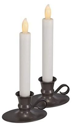 two white candles are sitting next to each other on a metal stand with one candle in the middle