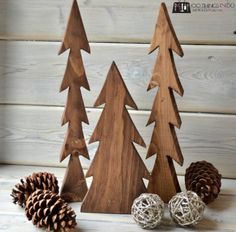 three wooden christmas trees with pine cones and balls