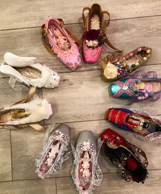 several pairs of shoes are arranged in a circle on the floor, all decorated with lace and beading