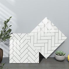 two white tiles sitting on top of a table next to a potted plant