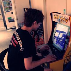 a young man sitting in front of a computer playing a game on the nintendo wii