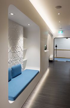 an empty waiting room with blue seats and white wallpaper on the walls, along with other furniture