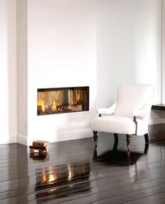 a white chair sitting in front of a fire place on top of a hard wood floor