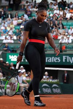 a woman holding a tennis racquet on top of a tennis court in front of a crowd