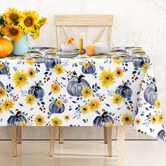 a table with sunflowers and pumpkins on it, next to a chair