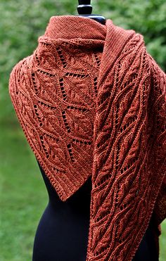 an orange knitted shawl on top of a mannequin dummy in the grass