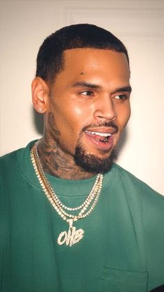 a close up of a person wearing a green shirt and a chain on his neck