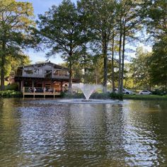 a large body of water with a house in the back ground and trees around it