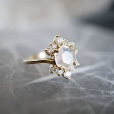 a close up of a gold ring with an opal and white diamond on it