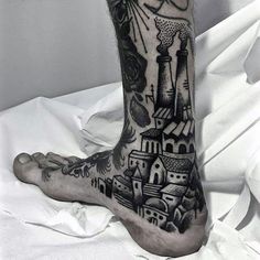 a black and white photo of a person's foot with a castle tattoo on it