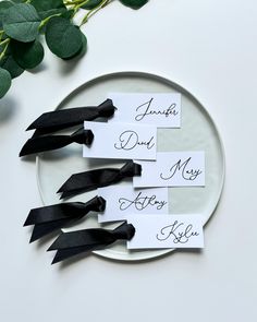 three place cards with black ribbons on a plate