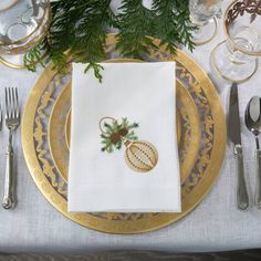 a place setting with silverware, napkins and pine cones on the tablecloth