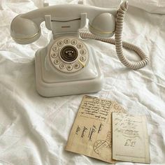 an old fashioned phone sitting on top of a bed next to a piece of paper