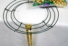 several gold and green beads are on a black wire rack with two bags of them