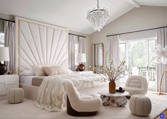 a bedroom with white furniture and chandelier hanging from the ceiling, along with large windows