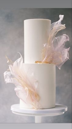 two tiered wedding cake with white frosting and pink feathers