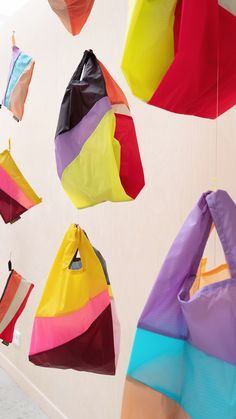 several colorful bags hanging from the ceiling in a room with white walls and flooring