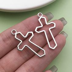 a person is holding two charms in their hand, one has a cross and the other has a man on it