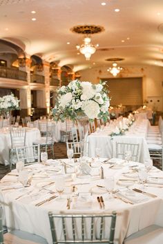 the tables are set with white flowers and silverware