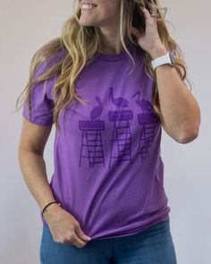 a woman talking on her cell phone while wearing a purple t - shirt with an image of two bunnies