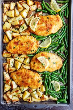 chicken, potatoes and green beans in a baking pan with lemons on the side