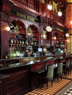 an old fashioned bar with lots of bottles and liquors on the shelves, along with checkered flooring