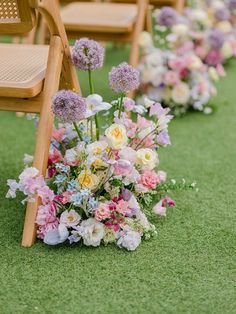 rows of wooden chairs lined up with flowers on the grass at an outdoor wedding ceremony