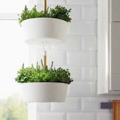 three white hanging planters with plants in them