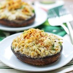 two white plates topped with stuffed mushrooms on top of a table next to silverware