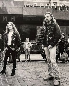 black and white photograph of two people standing in front of a building while others look on