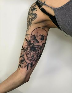 a man's arm with a skull and flowers tattoo on the left side of his arm